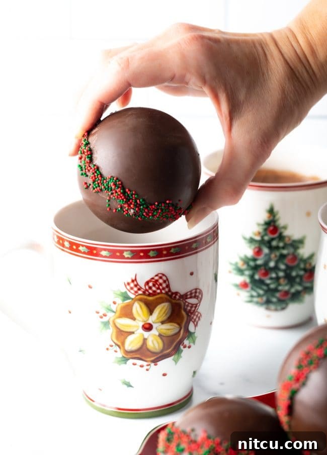 Magical Melting Cocoa 14 Hand holding hot chocolate ball over a Christmas mug.