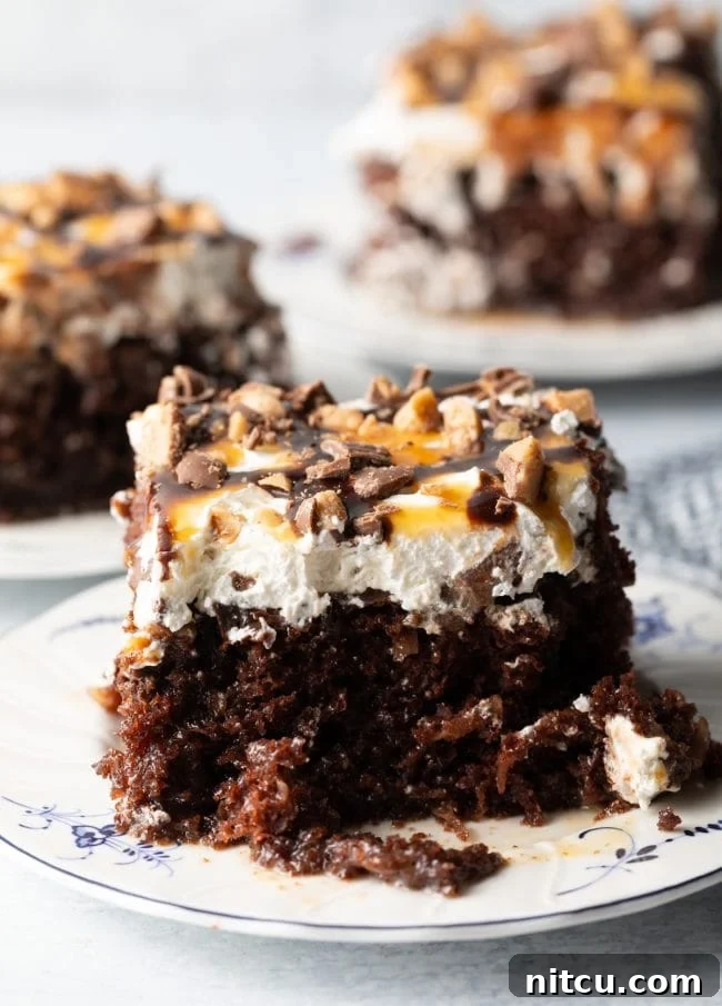 Sinfully Delicious Delight 2 Close-up view of a chocolate poke cake generously topped with whipped cream, caramel and chocolate sauce, and scattered with chopped Heath bars, promising a rich and indulgent experience.