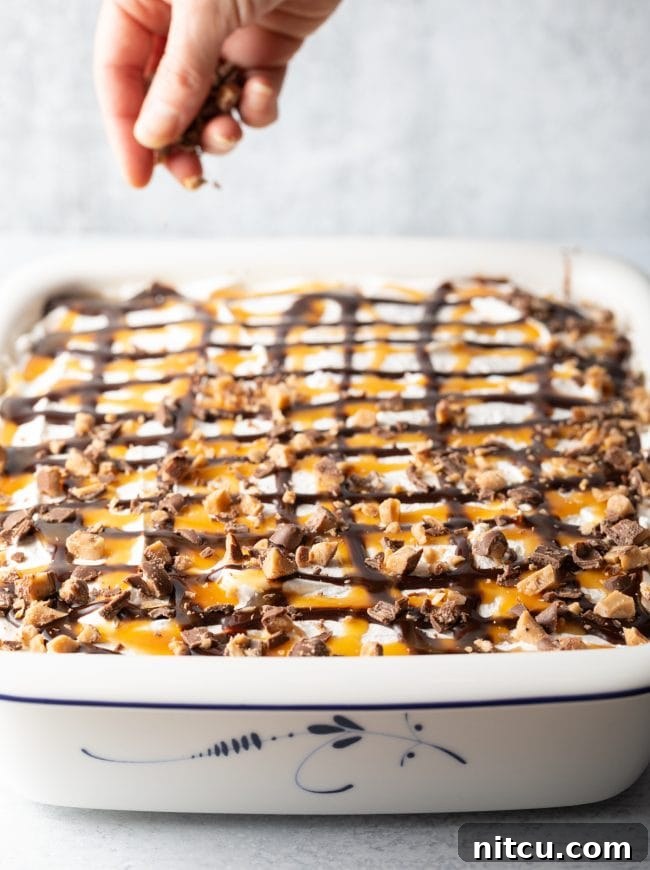 Sinfully Delicious Delight 11 A finished Better Than Sex Cake is shown with chopped Heath bars generously sprinkled on top of the creamy whipped cream, decadent chocolate sauce, and glistening caramel, highlighting its rich and irresistible layers.