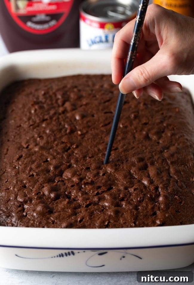 Sinfully Delicious Delight 6 A close-up shot shows a chopstick being used to carefully poke holes into the freshly baked Devil's food cake, preparing it for the decadent caramel soak.