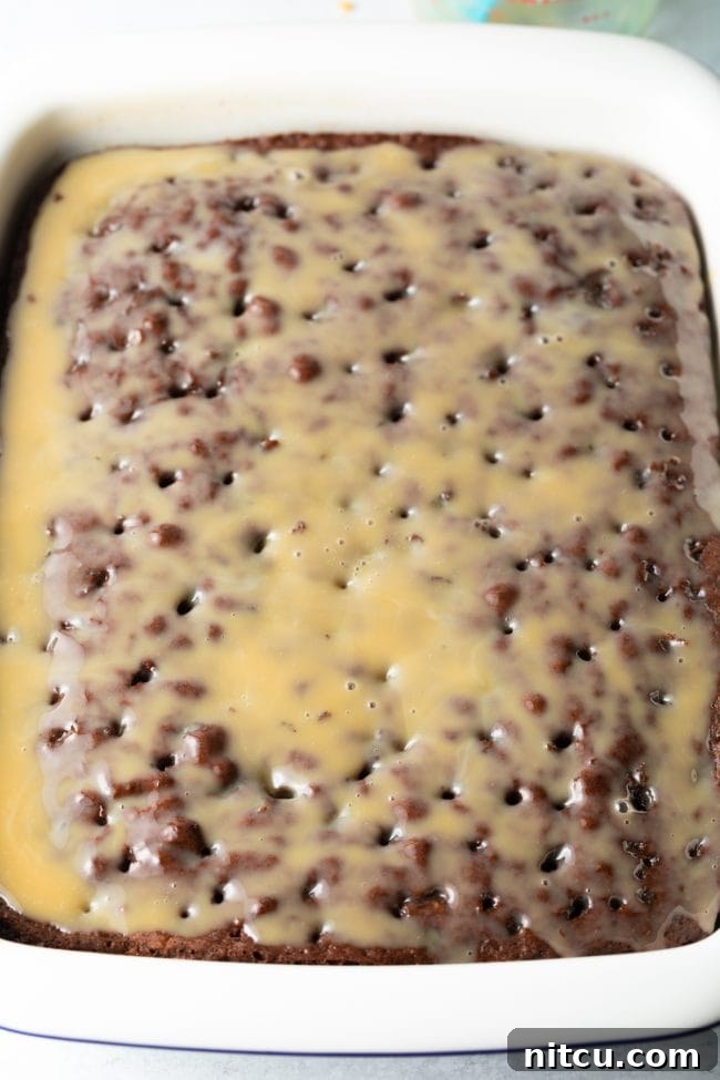 Sinfully Delicious Delight 8 A stream of rich caramel sauce is poured evenly over the surface of the poked cake, ensuring that every hole is filled and the cake is thoroughly saturated for maximum flavor and moisture.