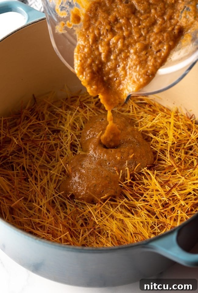 Mexican Fideo Noodle Bowl 9 pouring vibrant tomato puree from a blender jar into a large pot with browned fideo pasta noodles
