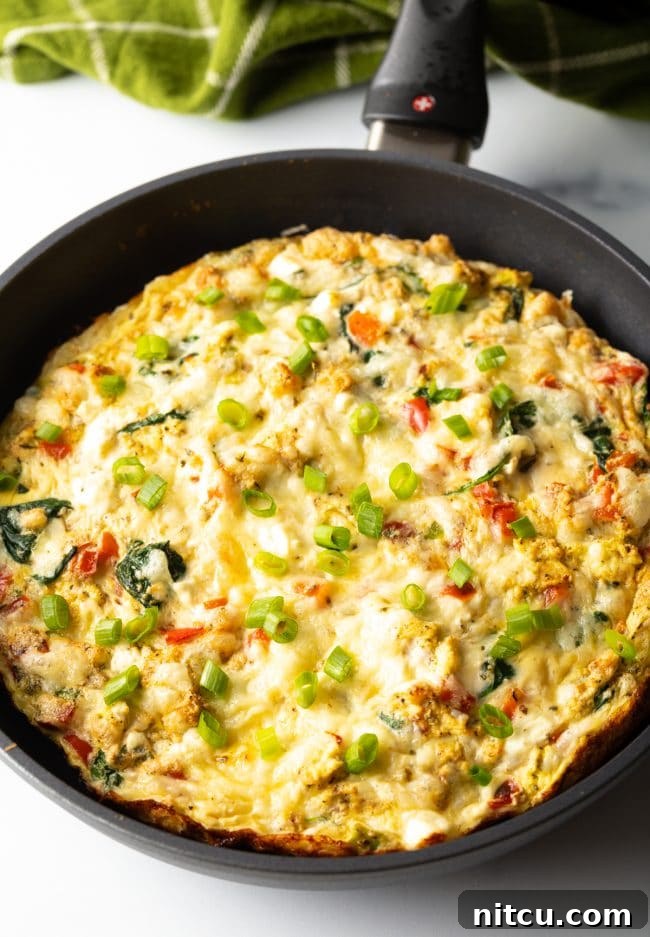 Baked egg white and peppers frittata in a cast iron skillet, puffed and golden