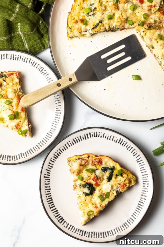 Top-down view of baked egg white spinach and veggie frittata slices on two plates with the full baked dish and spatula off to the side