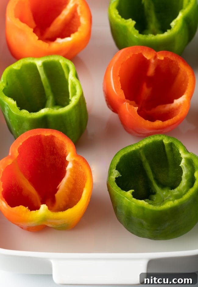 Savory No Rice Keto Beef Stuffed Peppers 4 Empty seeded red and green bell peppers in a baking dish.