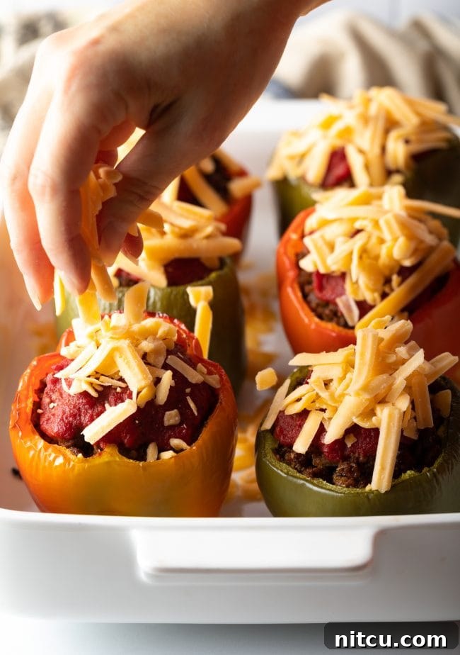 Savory No Rice Keto Beef Stuffed Peppers 9 Sprinkling shredded cheese onto to the keto stuffed peppers.