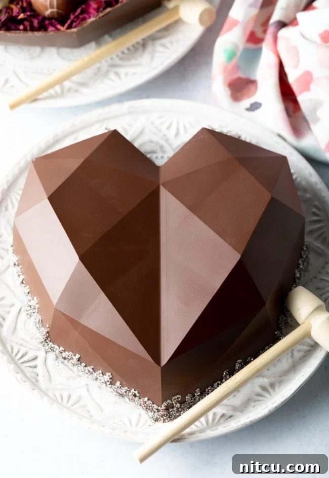 Crackable Chocolate Treasure 2 A beautifully crafted breakable chocolate heart, placed on a pristine white plate, accompanied by a small wooden hammer, ready for a delightful smash reveal.