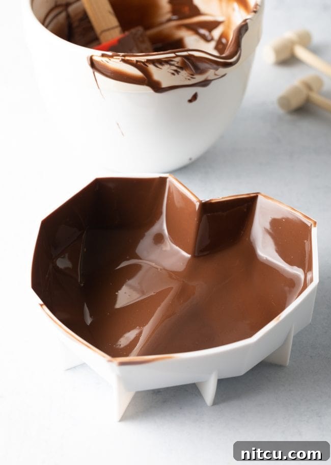 Crackable Chocolate Treasure 8 The interior walls of a heart mold are evenly coated with perfectly melted chocolate, forming a smooth, ready-to-set shell.