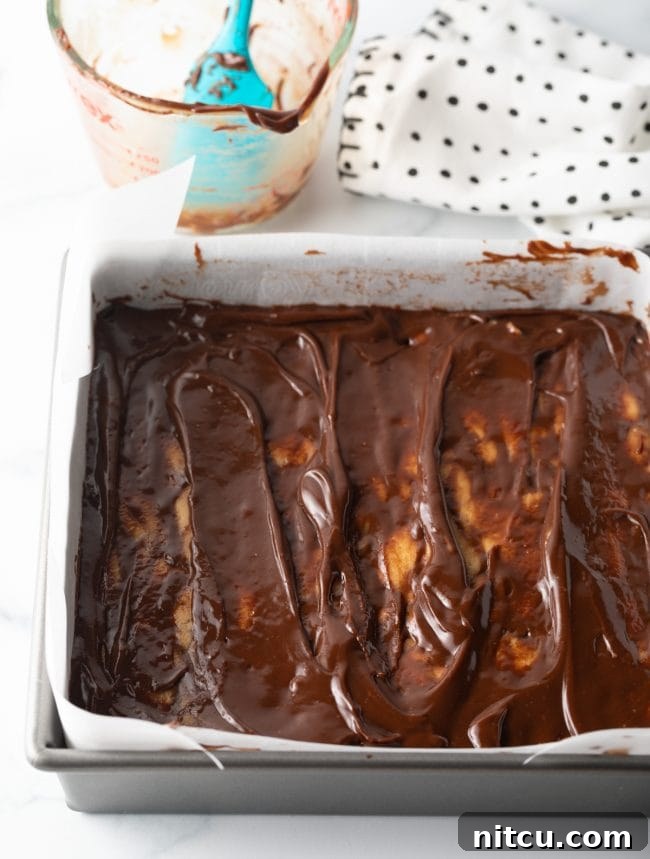 Peanut Butter Delights 11 Top-down view of melted chocolate fudge topping being added and swirled onto the peanut butter base in a baking pan.