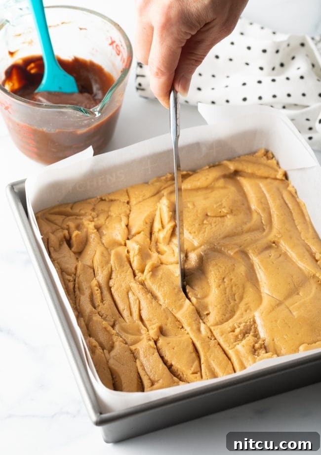Peanut Butter Delights 10 Spreading the peanut butter mixture in the baking pan and creating swirls with a knife for the chocolate layer.