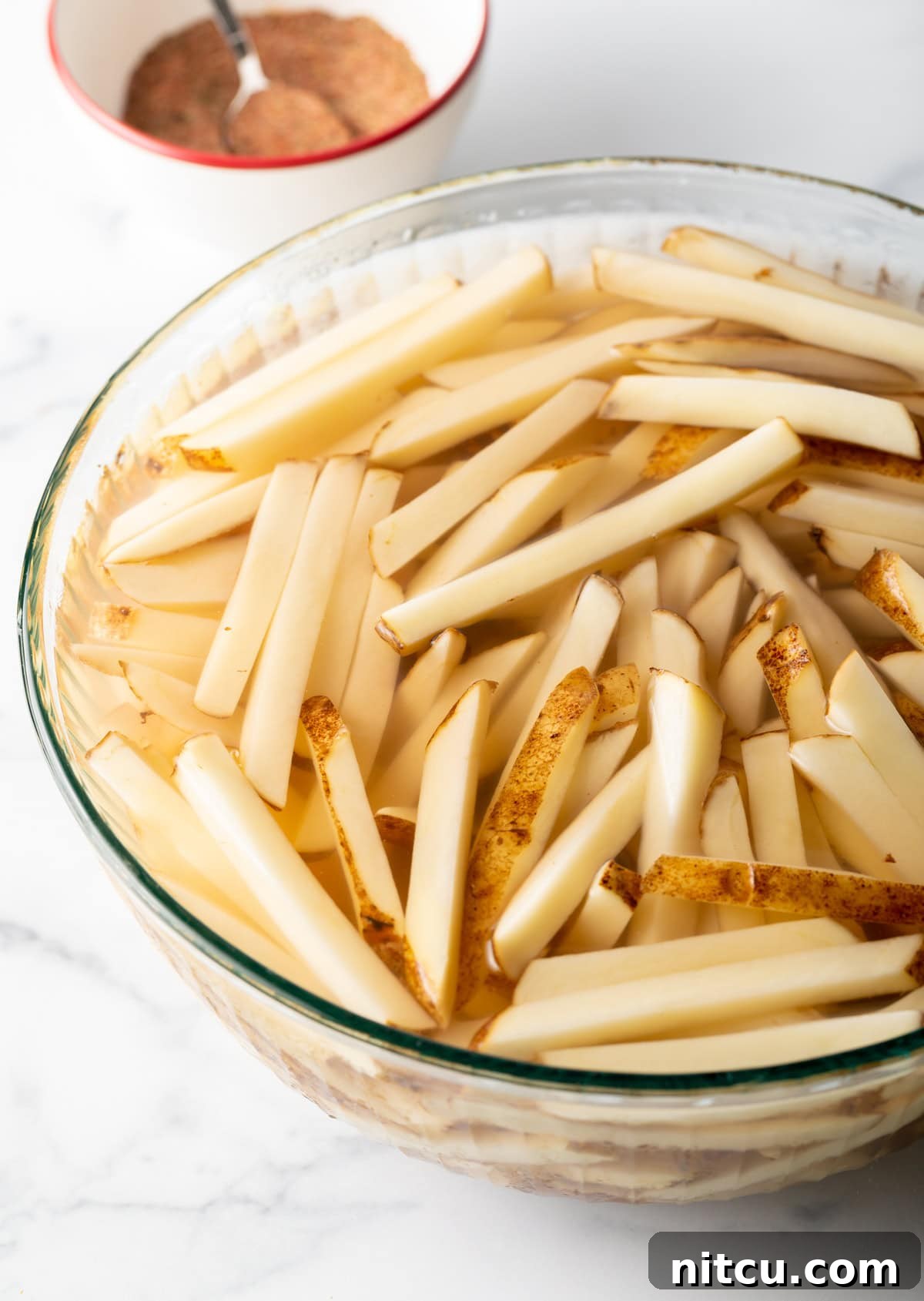 Cajun Fries: Homemade Seasoning Blend Recipe 6 Potato slices in soaking in a bowl of water.