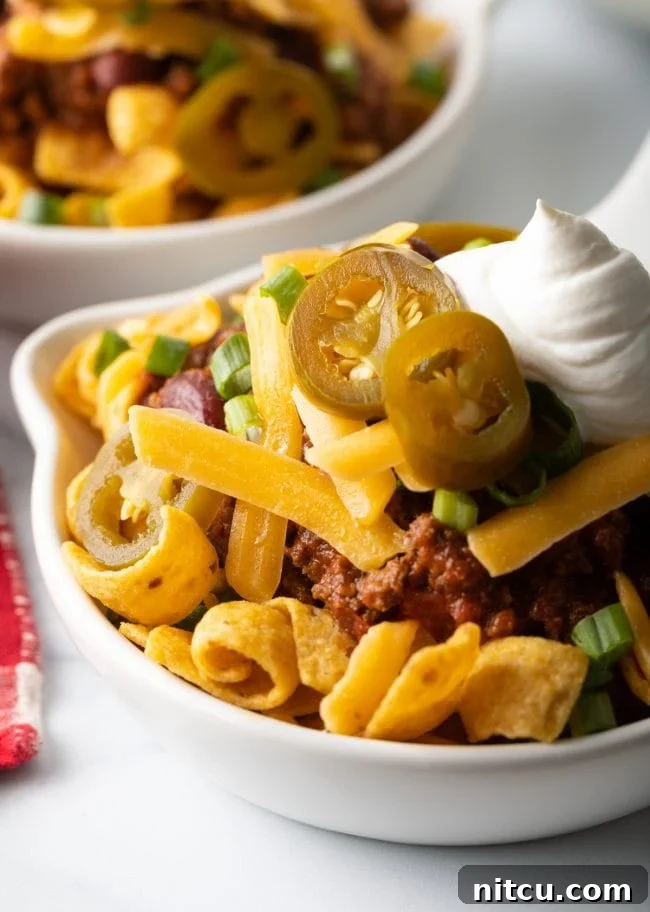 Ultimate Frito Chili Pie 2 Close view of Frito chili pie in a shallow bowl, showcasing the rich chili, melty cheese, and crunchy Fritos.