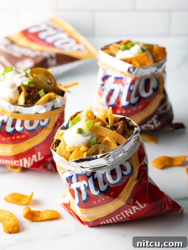 Ultimate Frito Chili Pie 11 Multiple Frito corn chip bags, each generously filled with chili, melted cheese, fresh scallions, and pickled jalapenos, showcasing the portable serving style.