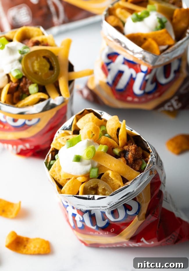 Ultimate Frito Chili Pie 3 Three individual bags of Fritos, each meticulously filled with Frito chili pie, ready to be served.