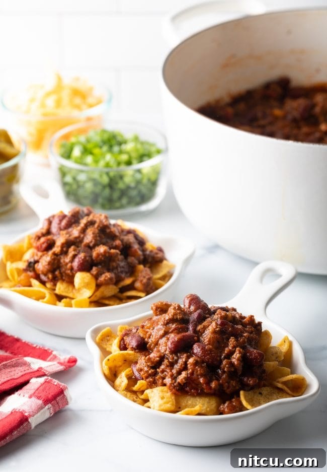 Ultimate Frito Chili Pie 8 Frito corn chips forming the base in a shallow bowl, topped with a generous scoop of hot, savory chili.