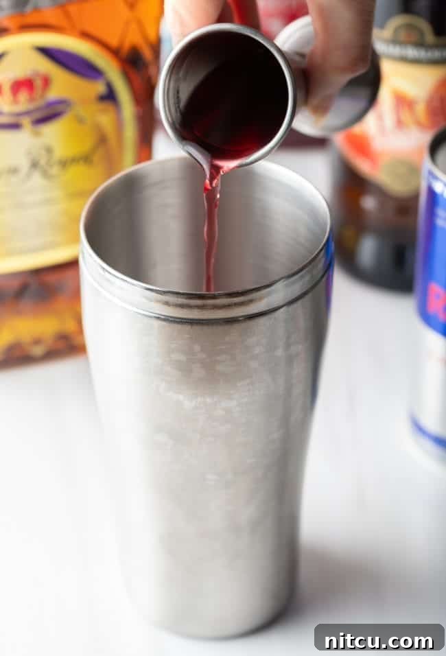 Sin City Slam 5 Closeup of hand pouring cranberry juice into a metal tumbler.