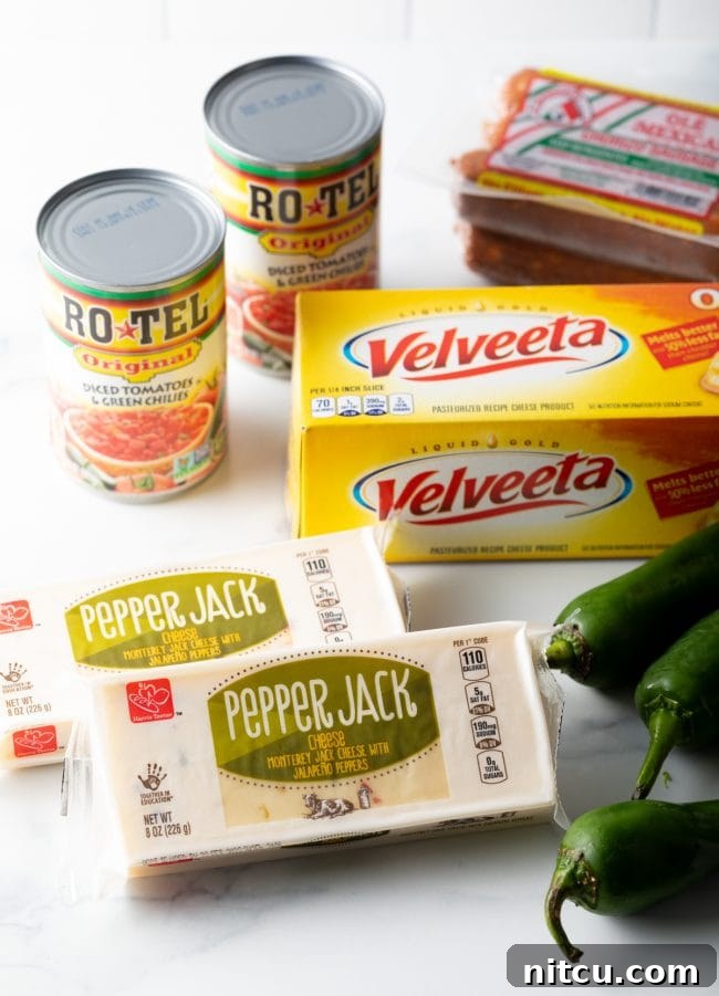 Pitmaster's Smoked Queso 4 A vibrant display of smoked queso ingredients: canned Rotel, blocks of Velveeta cheese, pepper jack cheese, and fresh jalapeños.