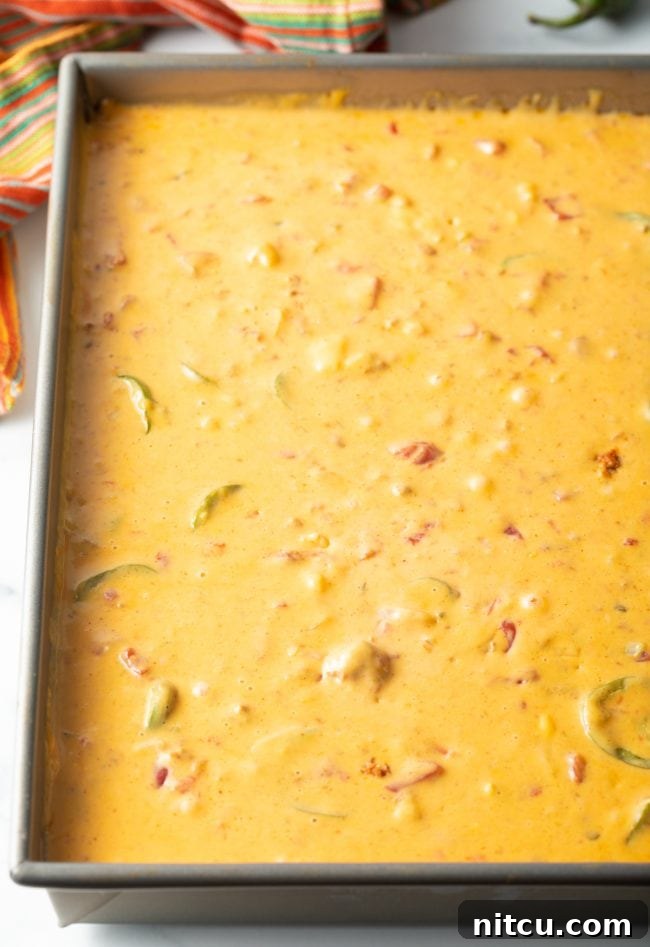 Pitmaster's Smoked Queso 7 Top view of a bubbling smoked queso chorizo dip presented in a rustic metal pan, ready to be enjoyed.
