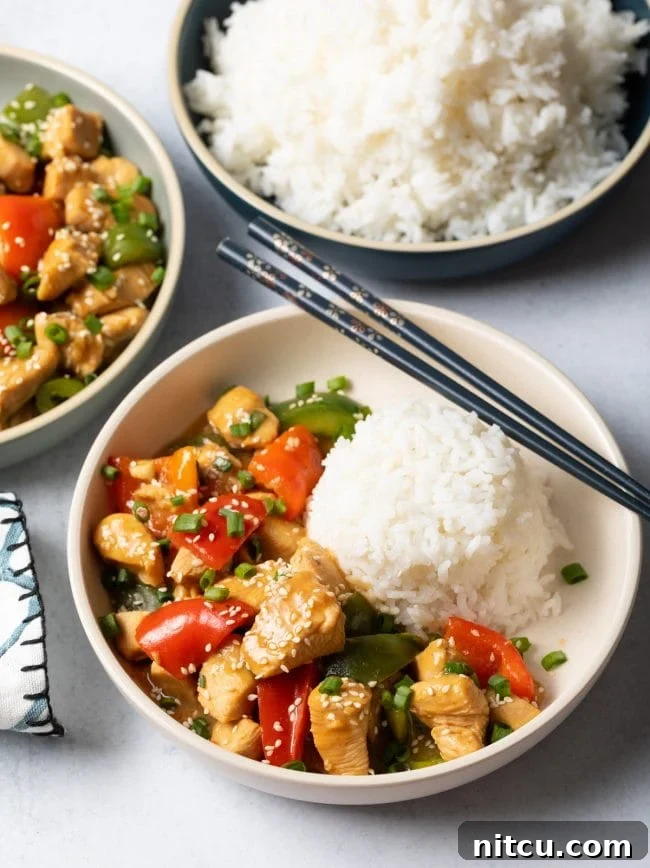 Top view two bowls of chicken with garlic sauce and veggies, each with scoop of white rice.