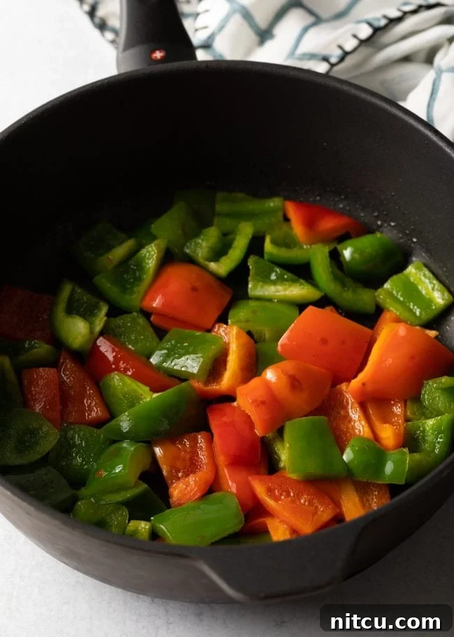 Large black skillet with chopped red and green bell peppers.