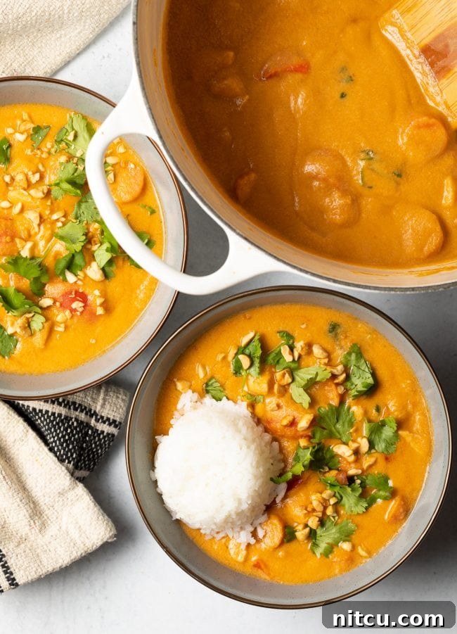 Authentic West African Maafe Peanut Stew 4 Top view of two bowls of African peanut soup with a scoop of rice nestled in each, ready to be enjoyed.