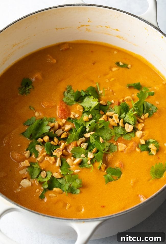 Authentic West African Maafe Peanut Stew 10 Finished Maafe soup in a pot, topped with fresh cilantro and crushed peanuts, ready to be served.