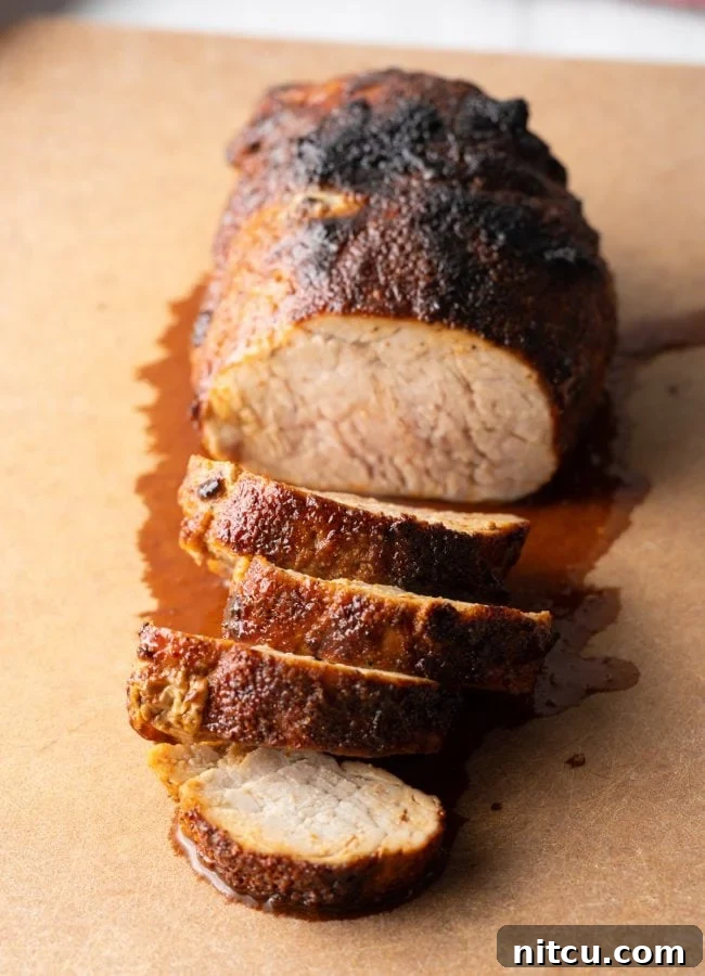A top-down view of a perfectly air-fried tenderloin, expertly sliced into juicy medallions, presented on a wooden cutting board.