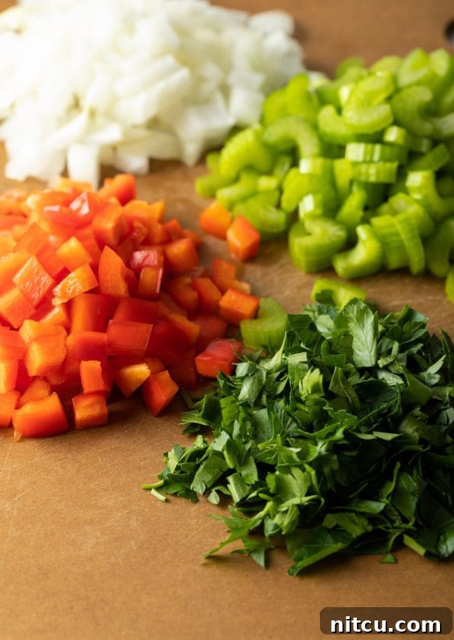 Soulful Cajun Dirty Rice 6 Chopped fresh ingredients including onion, celery, and bell pepper on a cutting board.