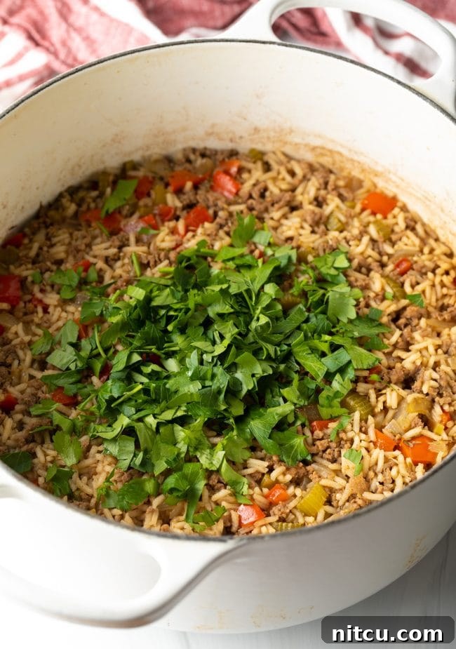 Soulful Cajun Dirty Rice 9 Finished cooked dirty rice in a pot, topped with fresh parsley.