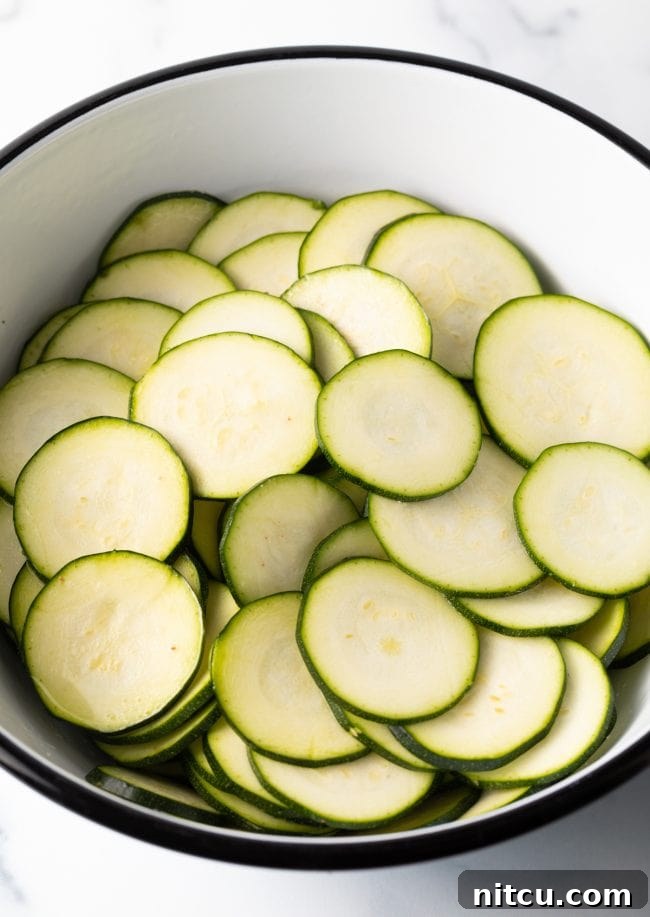 Crispy Air-Fried Zucchini Bites 6 A bowl filled with freshly sliced zucchini rounds, showing some moisture release after salting.