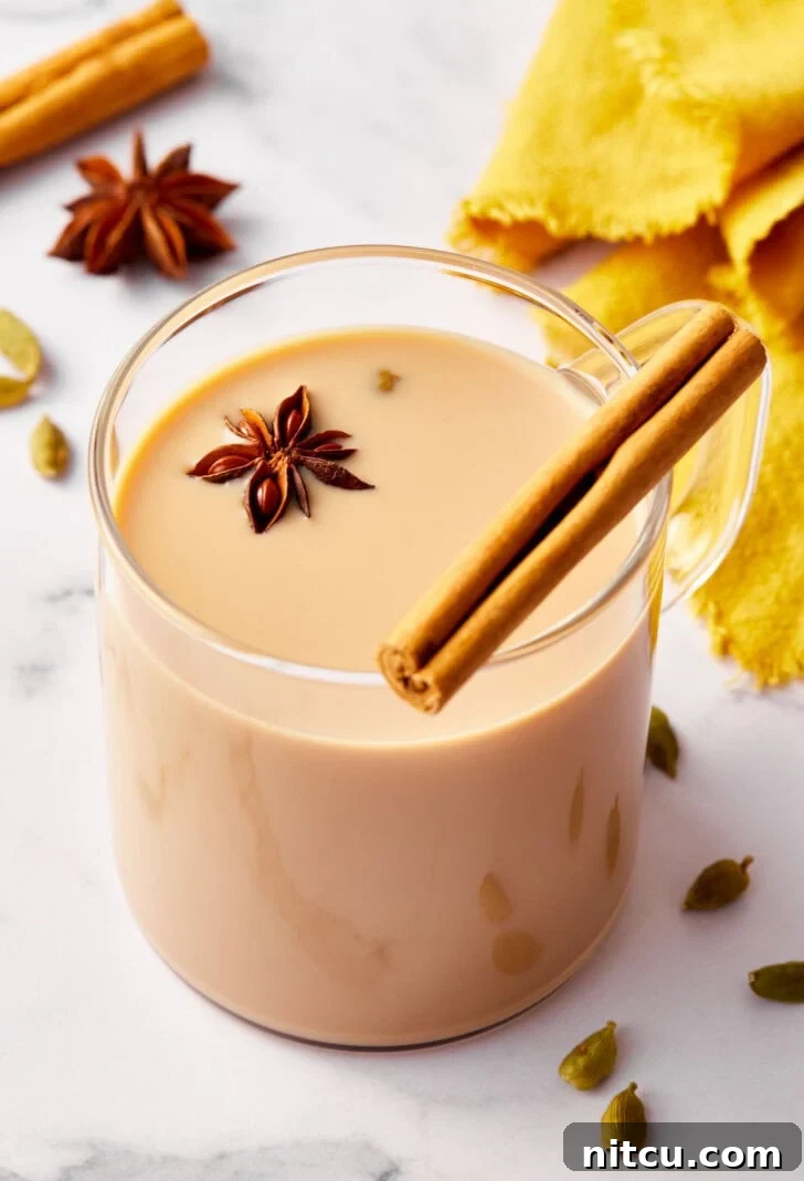 Finest Chai Tea Blends 12 Closeup of chai tea in a clear glass mug, elegantly garnished with a cinnamon stick and a star anise, highlighting its rich aroma.