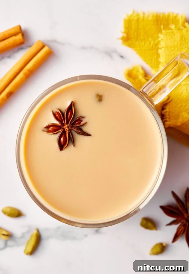 Finest Chai Tea Blends 13 Top-down view of a clear mug filled with foamy chai tea, garnished with a sprinkle of warming spices, highlighting its inviting aroma.