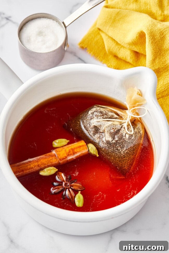 Finest Chai Tea Blends 5 Best Chai tea steeping in a large stock pot with cinnamon sticks, star anise pods, and cracked cardamom pods, infusing deeply aromatic flavors.