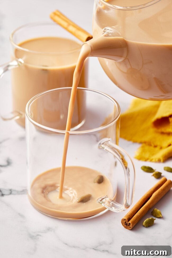 Finest Chai Tea Blends 9 Pouring a freshly made, creamy chai latte into a clear glass mug, ready to be enjoyed.