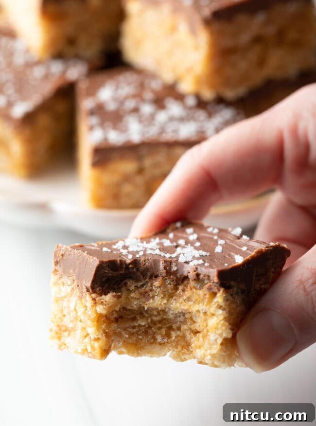 Peanut Butter Rice Krispie Treats 3 Hand holding Peanut Butter Rice Krispie Bar with bite taken to camera.