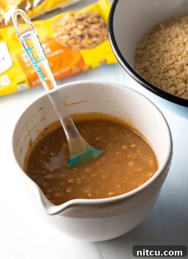 Peanut Butter Rice Krispie Treats 6 Large white measuring cup with melted butterscotch chips and peanut butter, combined with a spatula.