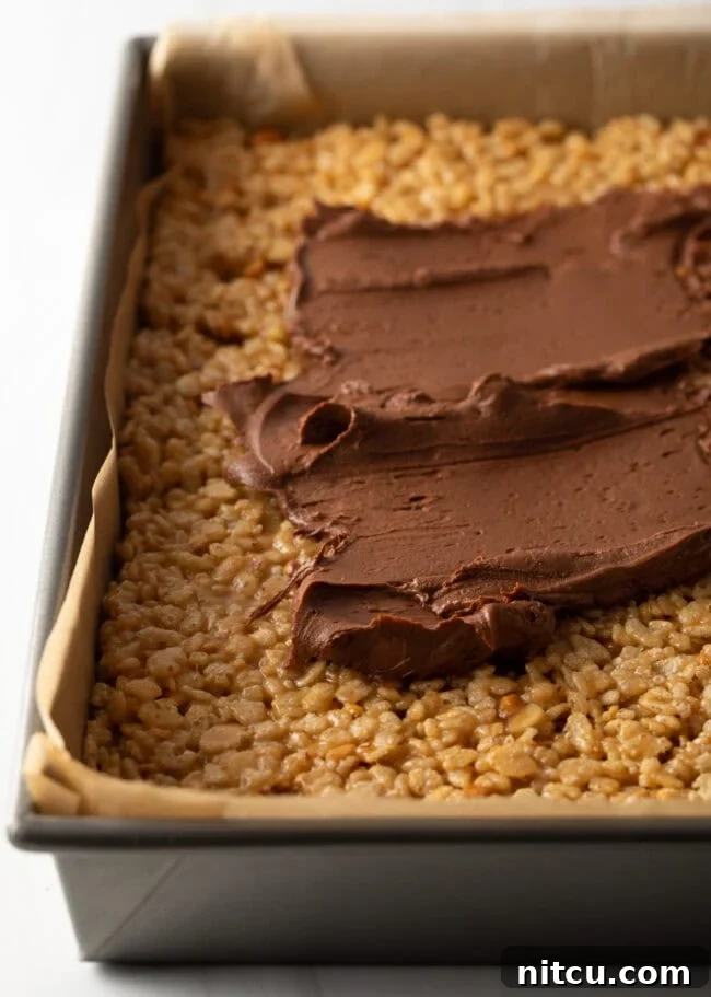 Peanut Butter Rice Krispie Treats 10 Spreading chocolate ganache on top of pressed cereal treats in a pan.