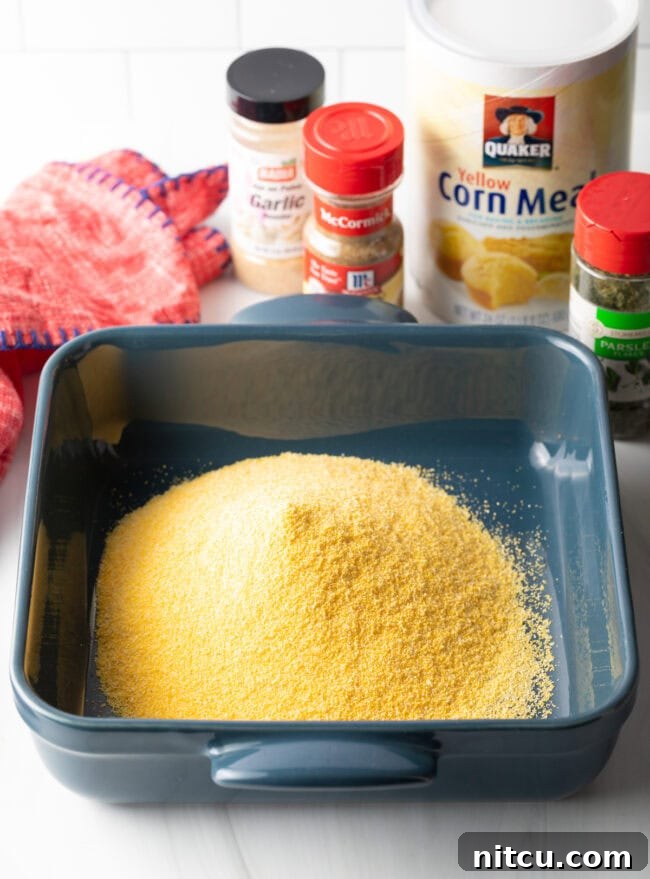 Crispy Corn-Crusted Fish 5 Square baking pan filled with golden yellow cornmeal, ready for seasoning.