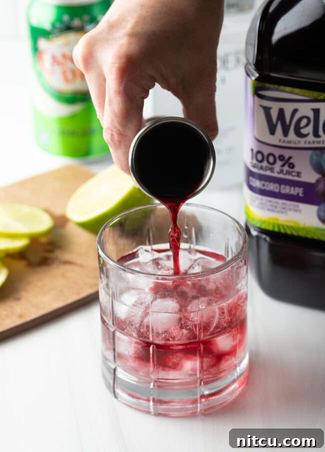 Lifeforce Infusion 7 A hand pouring purple grape juice into a glass with ice and vodka.