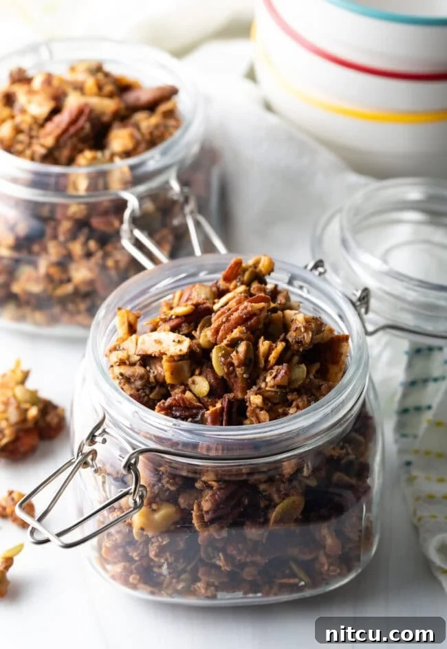Ultimate Keto Granola 2 Open glass jar brimming with homemade keto nut granola, showcasing its golden, crunchy texture.