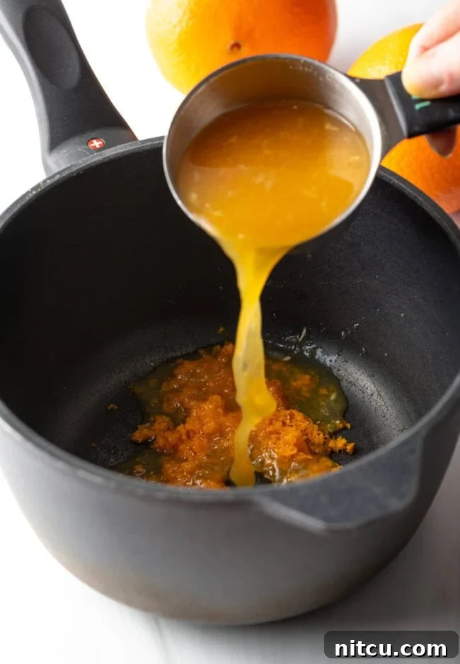 Sunshine Orange Curd 6 Hand pouring orange juice and zest into a pot. A hand carefully pouring freshly squeezed orange juice and fragrant zest into a saucepan. This visual highlights the initial step of combining the liquid citrus components with the zest, setting the stage for the curd's flavor development.