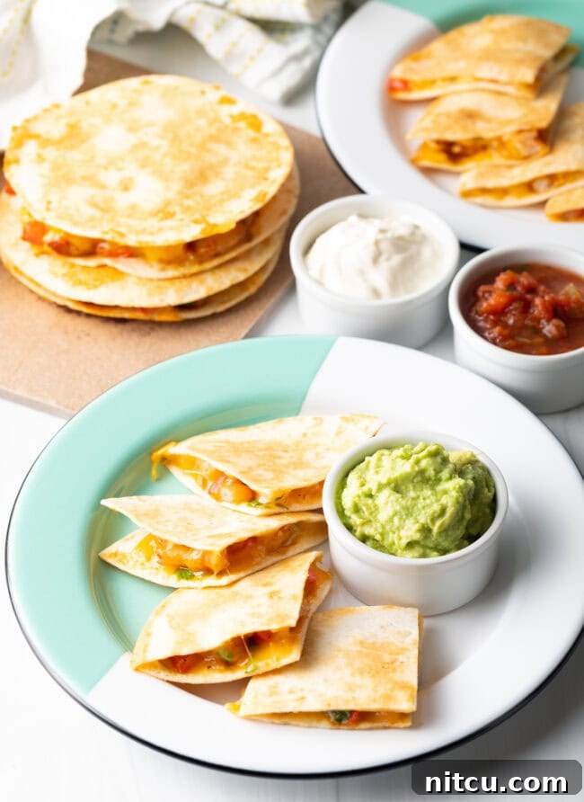 Effortless Shrimp Quesadilla Delight 11 Full spread of shrimp quesadillas on plates, stacked in background, ramekins of guacamole, sour cream, and salsa.