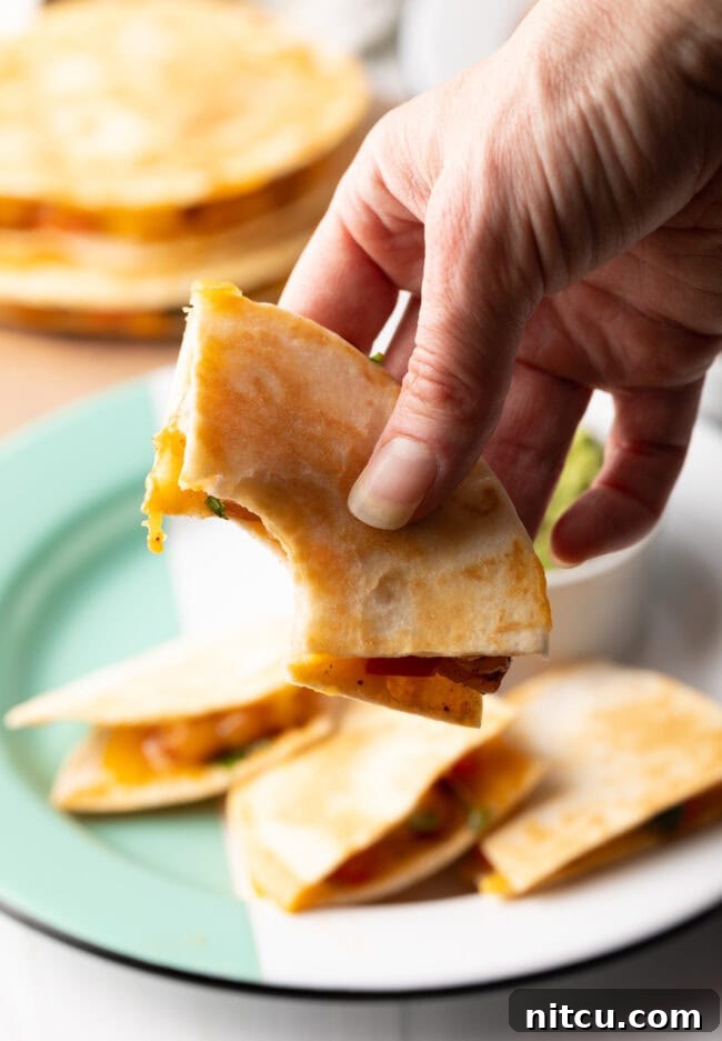 Effortless Shrimp Quesadilla Delight 12 Hand holding quesadilla to camera with bite taken out.