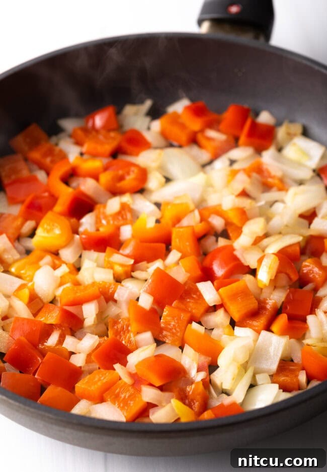 Effortless Shrimp Quesadilla Delight 5 Chopped onions and red pepper in a skillet.