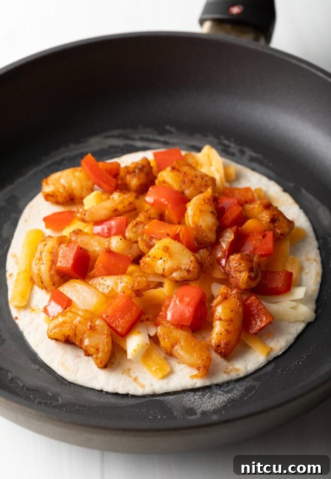 Effortless Shrimp Quesadilla Delight 7 Skillet with tortillas, topped with cheese, peppers and shrimp.