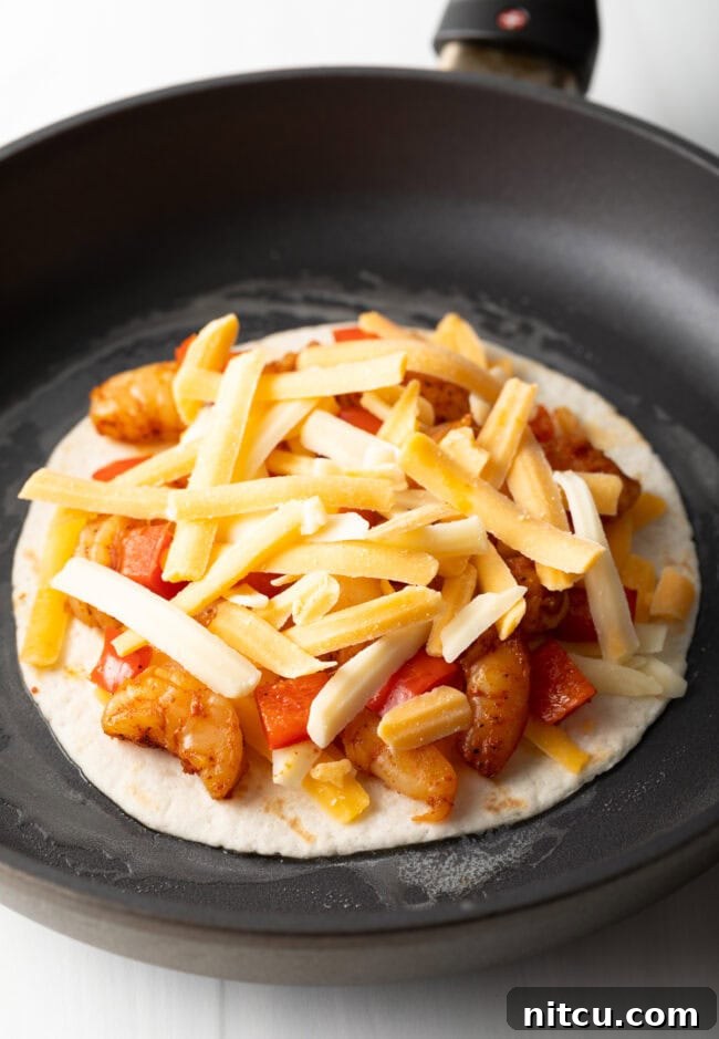 Effortless Shrimp Quesadilla Delight 8 More cheese added to tortilla in a skillet.