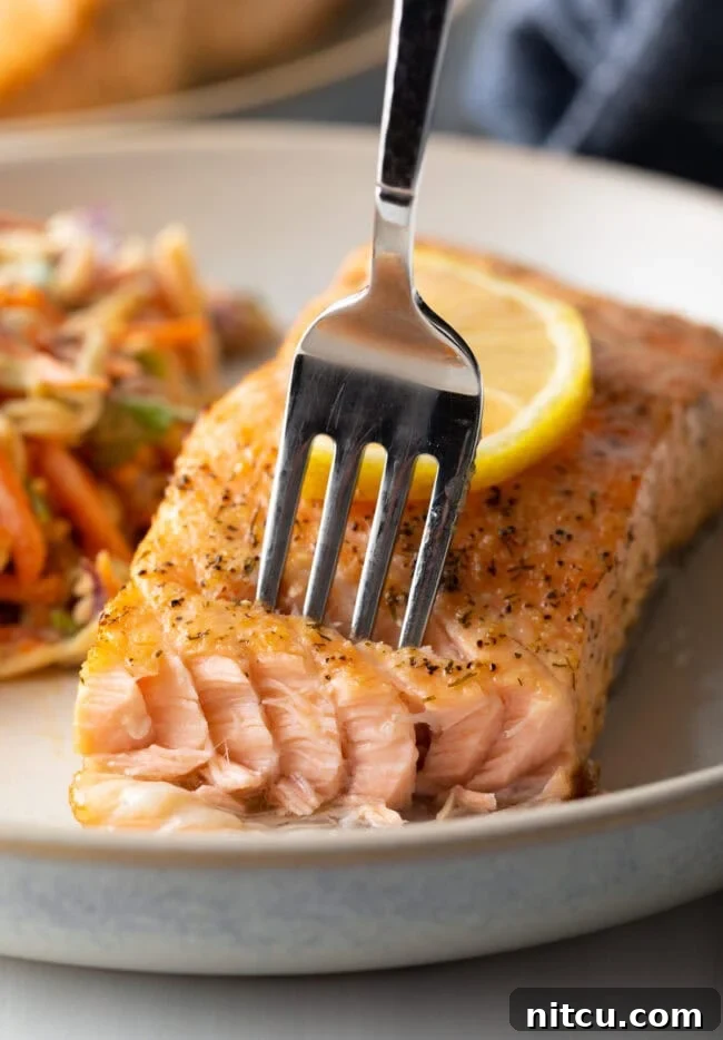 Crispy Skin Air Fryer Frozen Salmon 12 Fork taking a bite of salmon. Crispy skin, flaky meat.