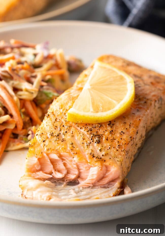 Crispy Skin Air Fryer Frozen Salmon 4 Piece of fish with bite taken out, on a plate. Air fryer salmon with crispy skin.