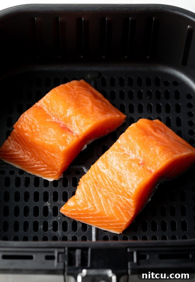 Crispy Skin Air Fryer Frozen Salmon 6 Two uncooked salmon fillets in the air fryer, ready for cooking.