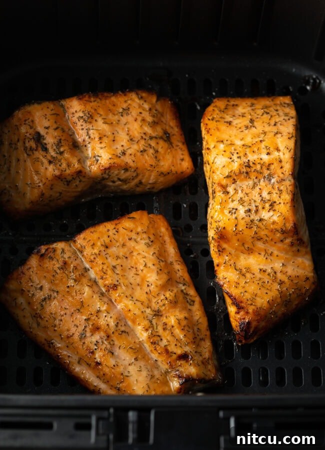 Crispy Skin Air Fryer Frozen Salmon 8 Cooked salmon fillet in the air fryer basket, perfectly golden.